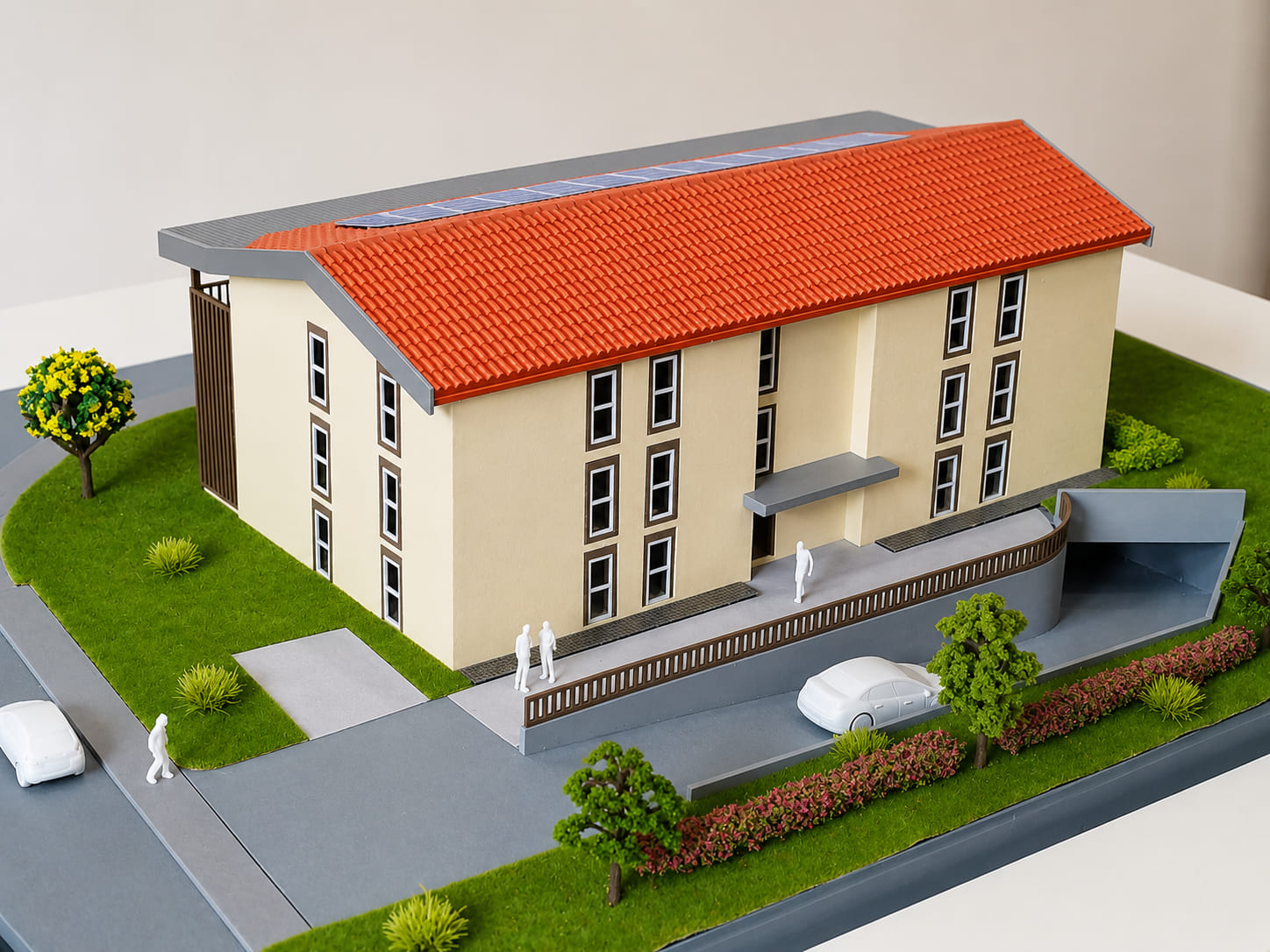 Maquette architecturale sur mesure d’un bâtiment résidentiel avec toiture rouge, espaces verts et accès
