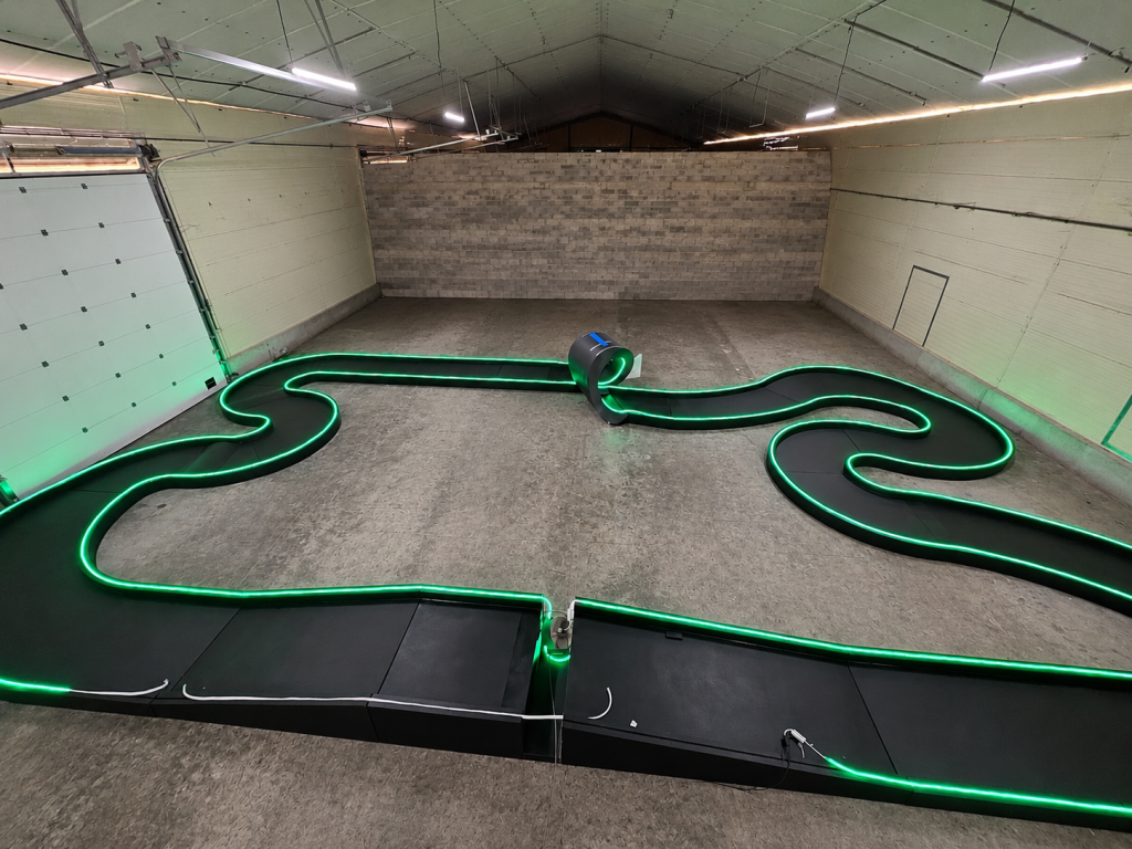 Circuit XL Exost pour voitures radio-télécommandées avec tubes LED verts intégrés et looping, testé en atelier avant installation sur salon.