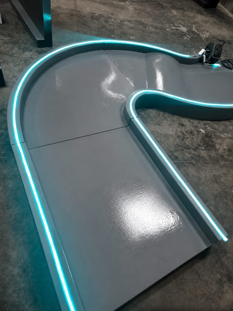 Module courbe du circuit XL Exost en résine grise avec tubes LED bleus intégrés pour voitures radio-télécommandées.